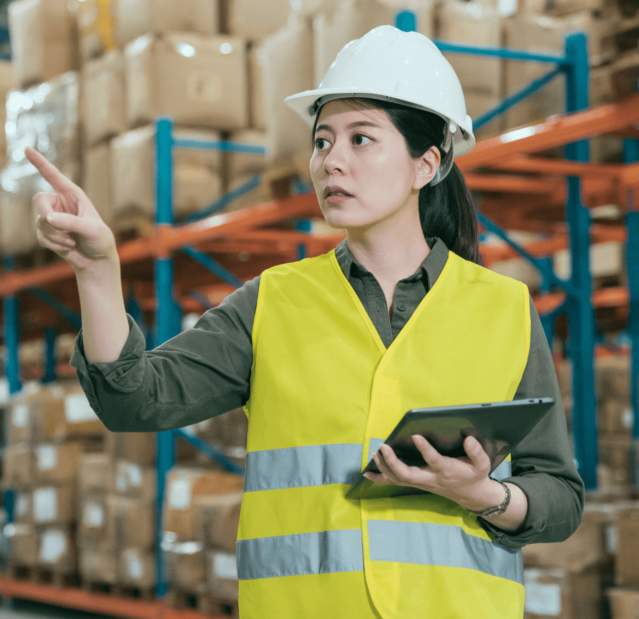 Woman in a hardhat pointing in a warehouse